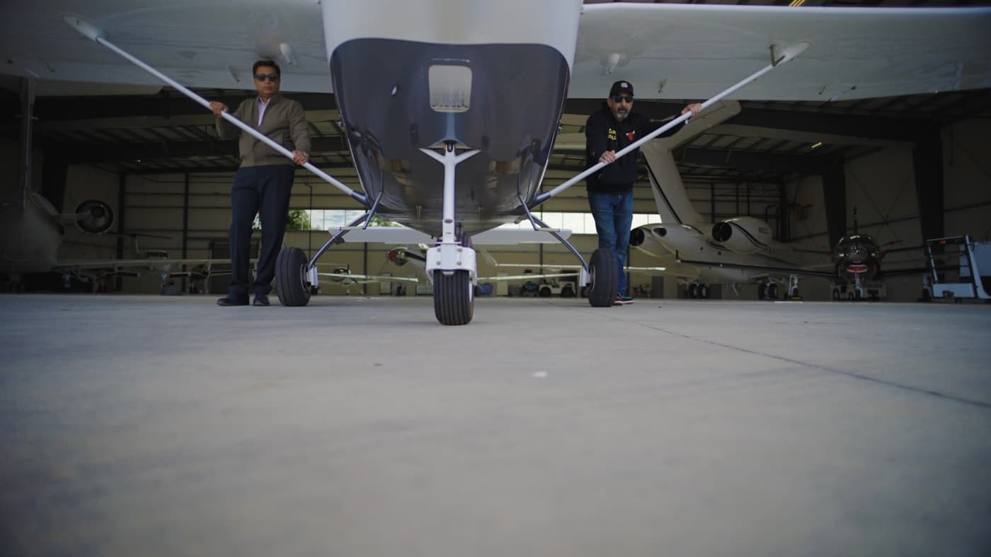 Technicians working on a small aircraft inside a hangar