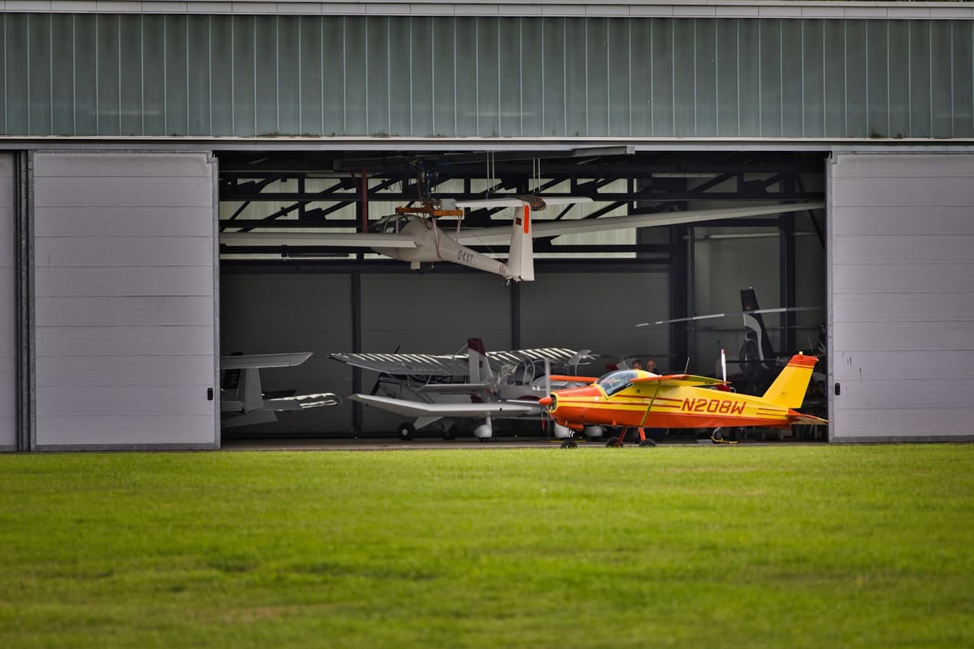 Small aircraft parked inside a wide maintenance hangar
